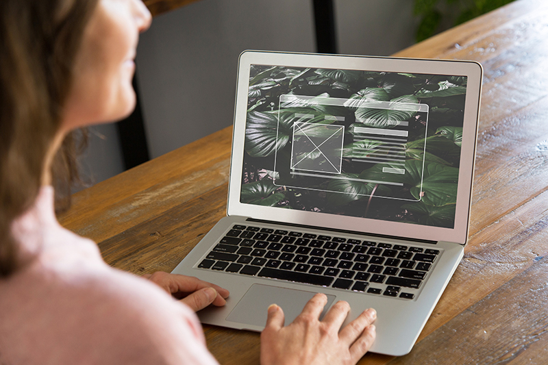 Girl sitting in front of a laptop with Elementor UI on the screen